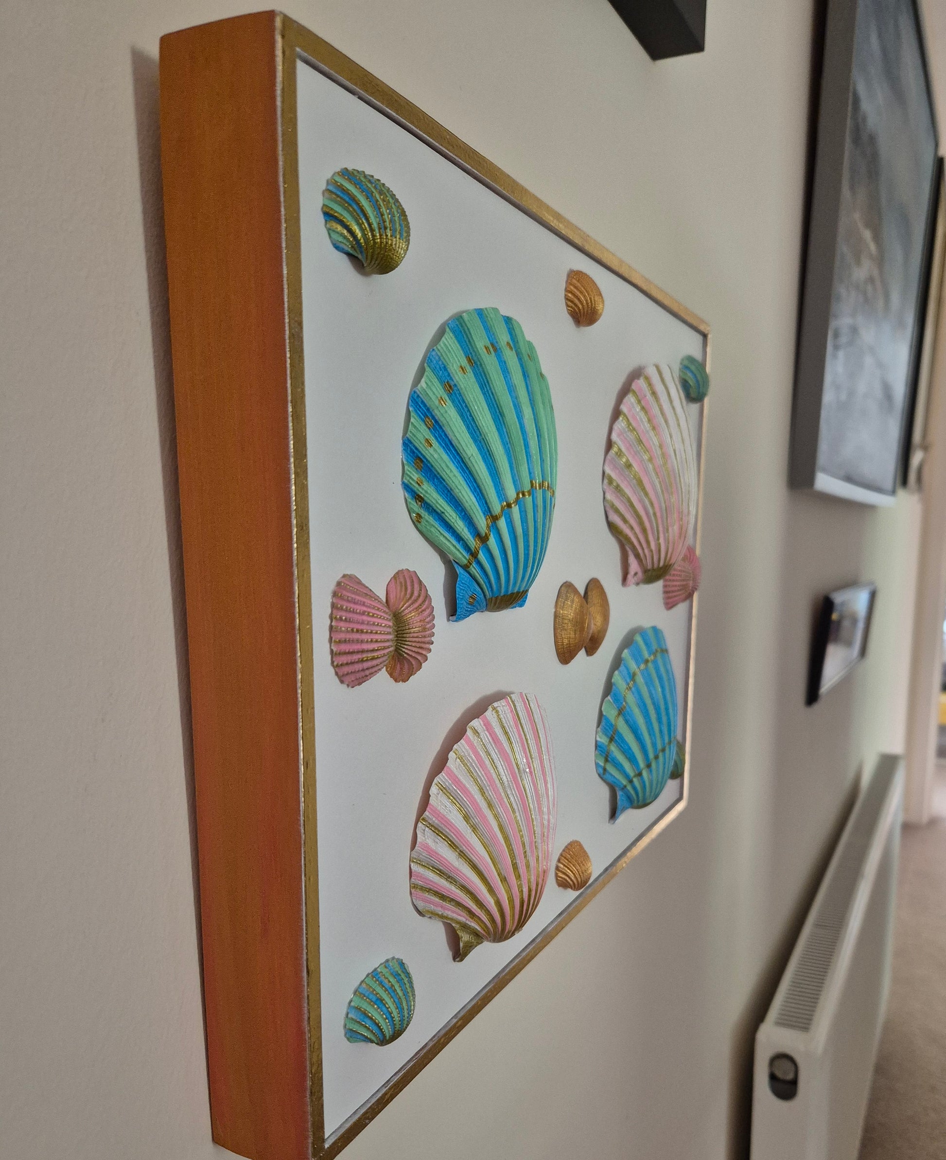 Framed artwork with colorful shell designs on a wall.